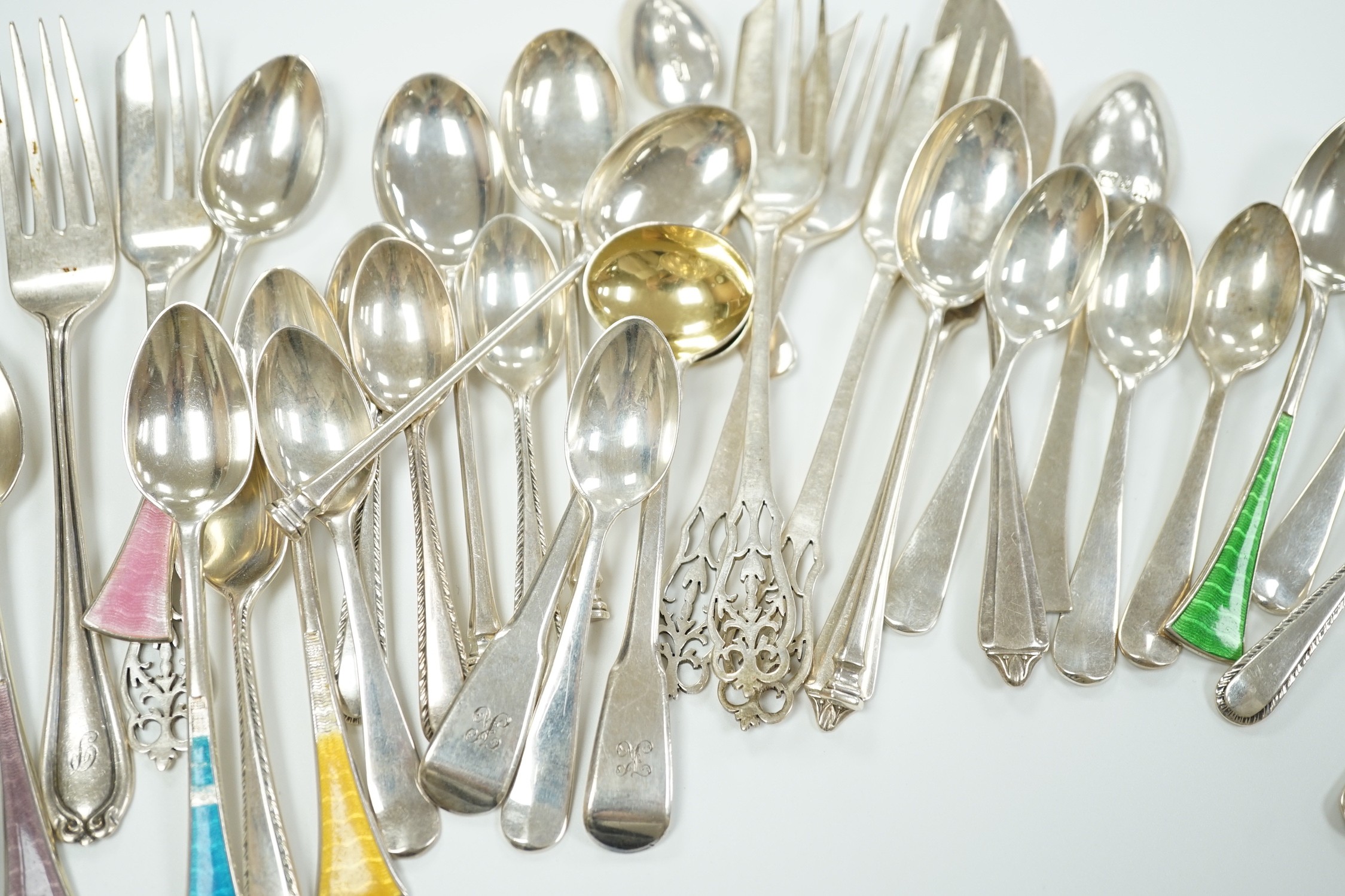 A small collection of assorted silver flatware including teaspoons, enamelled spoons(a.f.), butter knives, pastry forks and a pair of continental 830 white metal cake tongs, gross weight 14.4 oz.